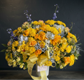Bouquet of yellow and orange flowers with a yellow ribbon on a dark background
