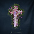 Floral arrangement in the shape of a cross with purple and pink flowers on a black background