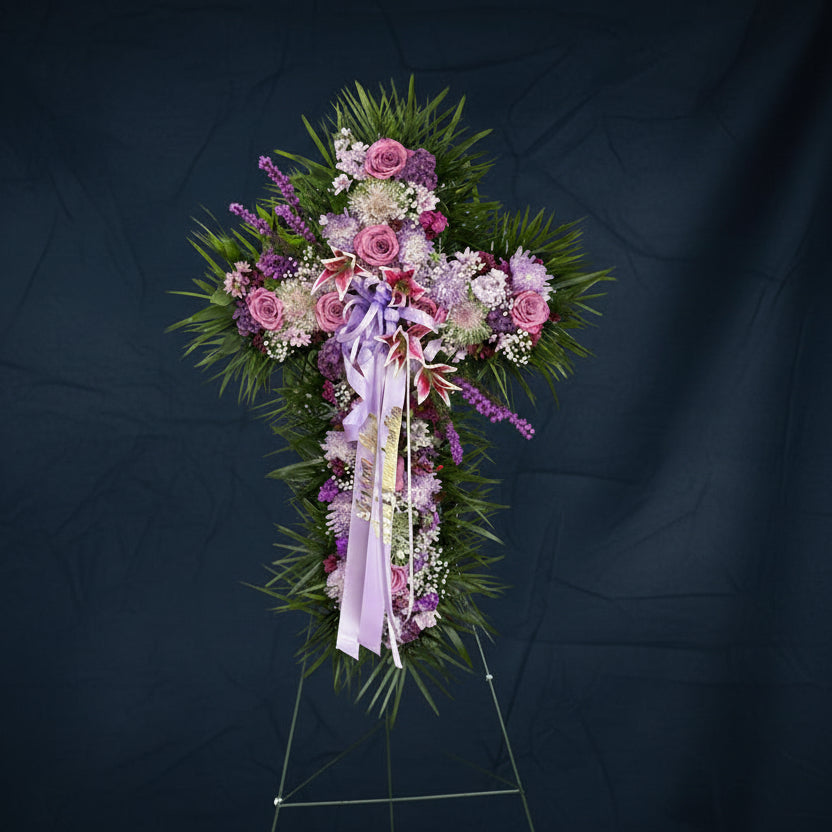 Floral arrangement in the shape of a cross with purple and pink flowers on a black background