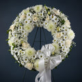 Floral wreath with white flowers and a white ribbon on a black background