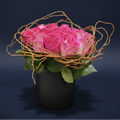 Pink roses in a black vase with decorative twigs on a dark background